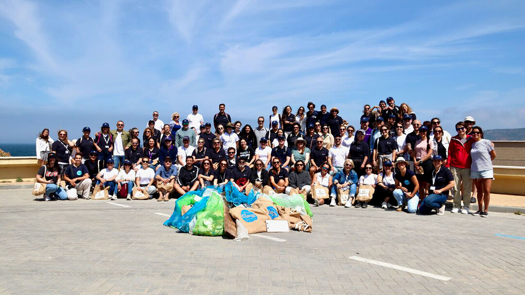 Construir Comunidades Mais Saudáveis: Colegas a passarem tempo de qualidade juntos enquanto contribuem para a comunidade numa ação local de limpeza de praia.